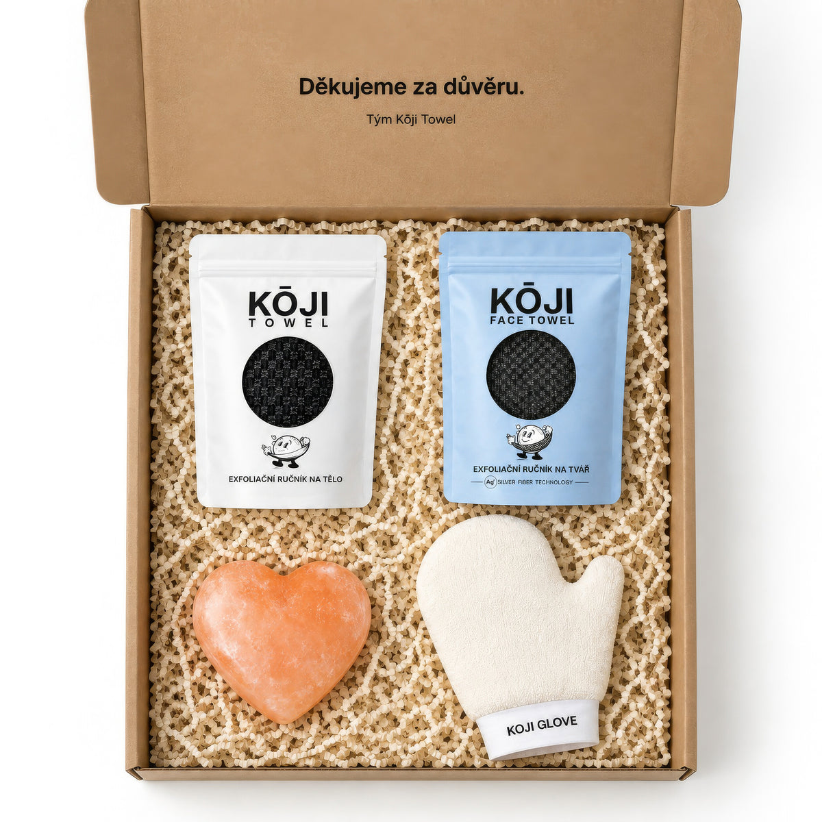 Pohled shora do otevřené krabice Kōji — čtyři produkty sady rozložené v papírové výplni.