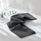 Exfoliační ručník Kōji Face Towel rozvlněný na světlém pozadí